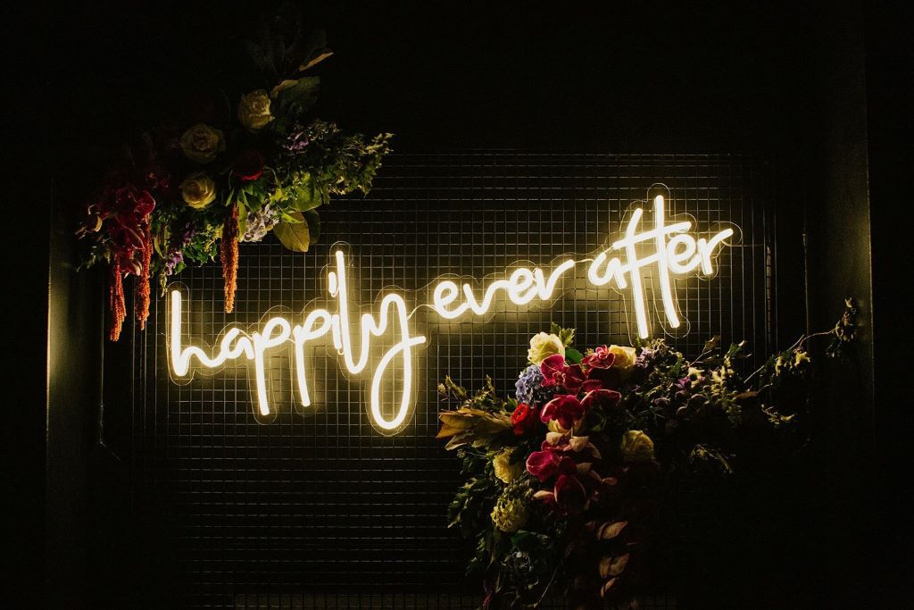 Personalized wedding neon sign displayed behind the sweetheart table at a modern reception